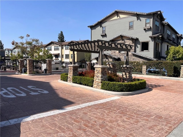 view of property's community featuring a gate, fence, and a pergola