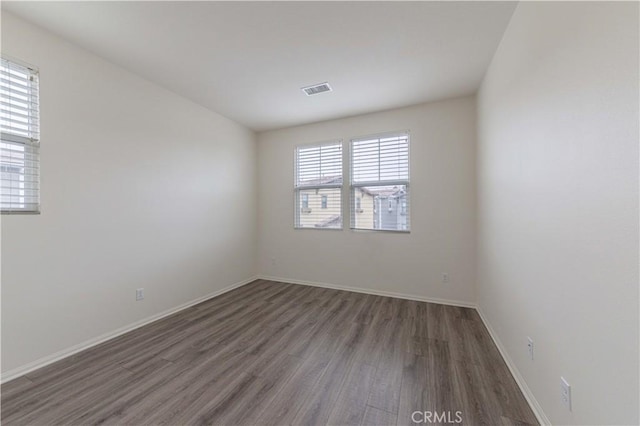 empty room with visible vents, baseboards, and wood finished floors