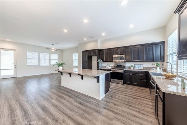 kitchen featuring a kitchen breakfast bar, plenty of natural light, appliances with stainless steel finishes, a sink, and open floor plan