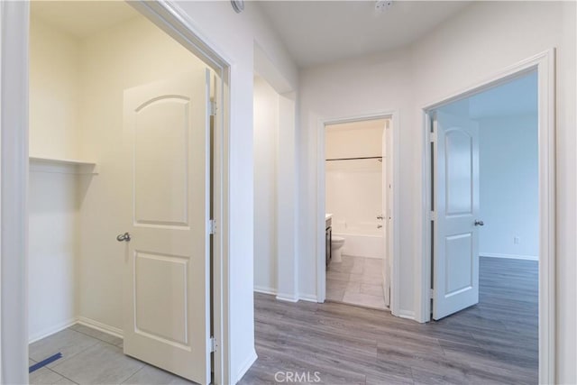 hallway featuring light wood-type flooring and baseboards