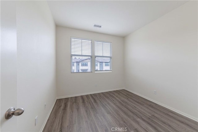 spare room with baseboards, wood finished floors, and visible vents
