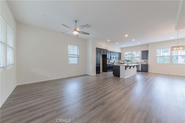 unfurnished living room with baseboards, a ceiling fan, recessed lighting, and wood finished floors