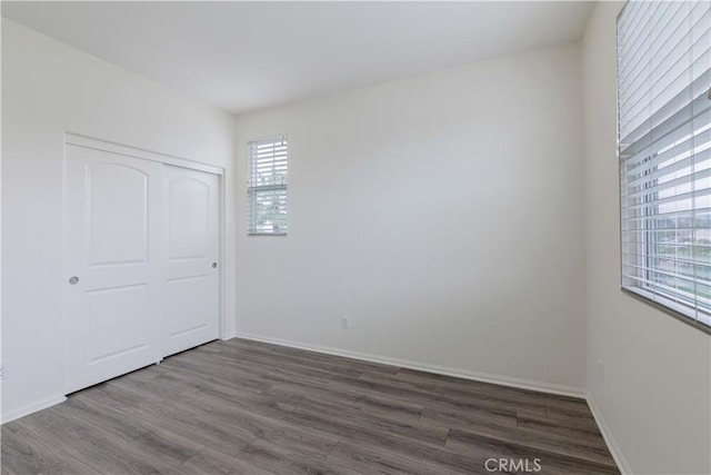 unfurnished bedroom featuring baseboards, a closet, and wood finished floors
