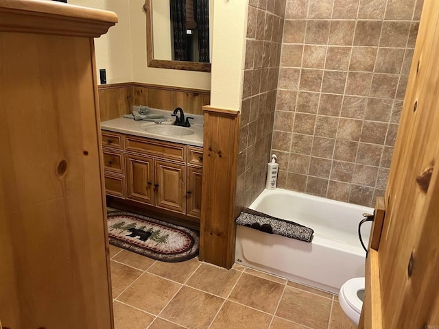bathroom featuring a wainscoted wall, shower / washtub combination, wooden walls, toilet, and vanity