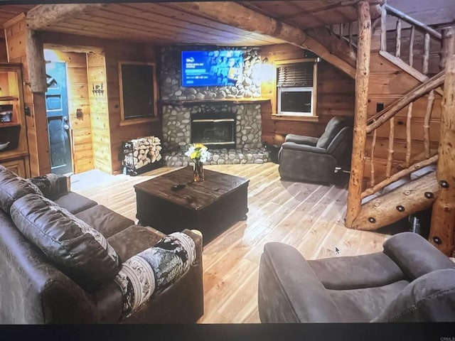 living area featuring wood ceiling, a stone fireplace, hardwood / wood-style floors, and wooden walls