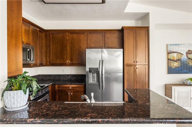 kitchen featuring appliances with stainless steel finishes, dark stone countertops, and a textured ceiling