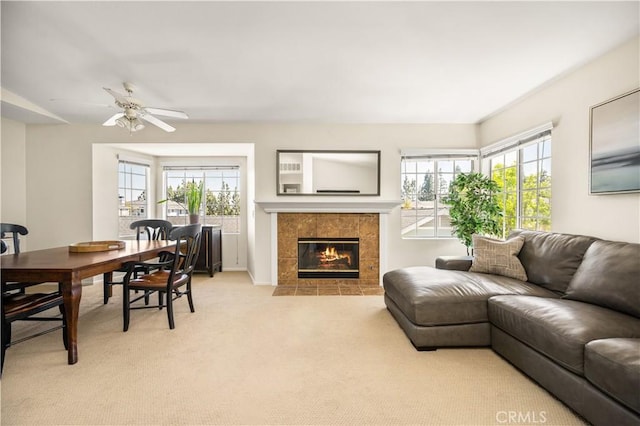 living room featuring a fireplace, a ceiling fan, and light colored carpet