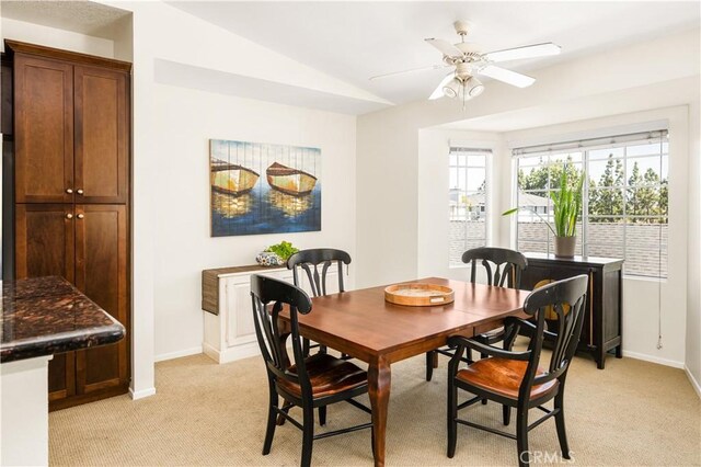 dining area with baseboards, ceiling fan, vaulted ceiling, and light colored carpet