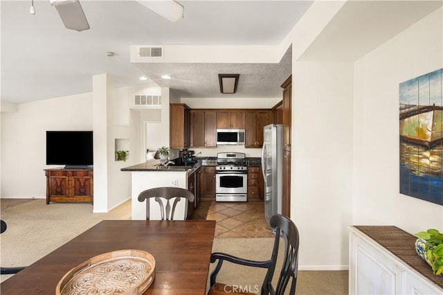 kitchen featuring stainless steel appliances, visible vents, open floor plan, and light carpet