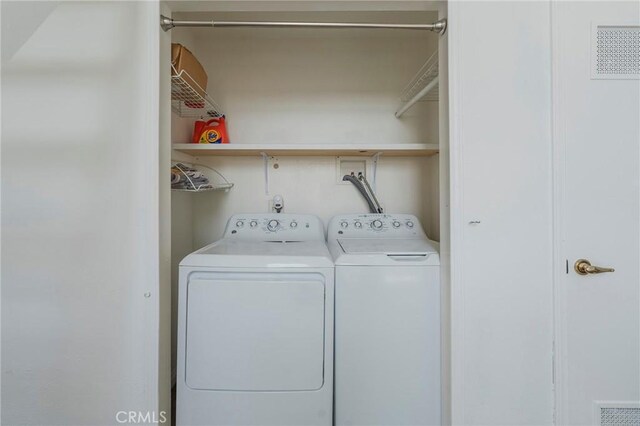 clothes washing area featuring washer and dryer, visible vents, and laundry area