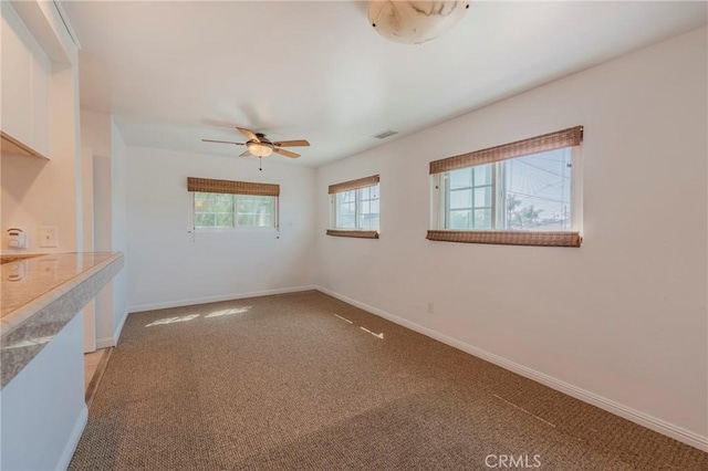 spare room with visible vents, a ceiling fan, and light colored carpet