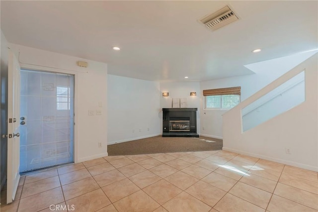 unfurnished living room featuring a glass covered fireplace, visible vents, light tile patterned floors, and recessed lighting