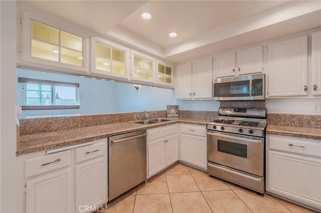 kitchen with a sink, light tile patterned floors, glass insert cabinets, white cabinets, and appliances with stainless steel finishes