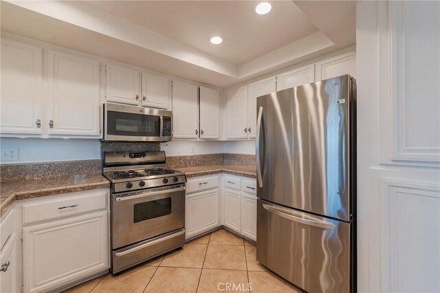 kitchen featuring white cabinets, dark countertops, stainless steel appliances, light tile patterned flooring, and recessed lighting