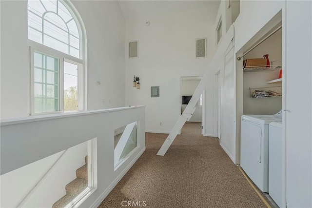 corridor featuring carpet flooring, baseboards, visible vents, a high ceiling, and washer and clothes dryer