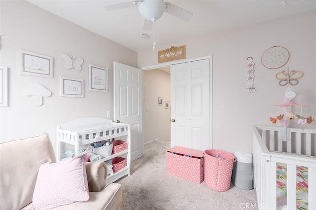 carpeted bedroom with a nursery area, a closet, and ceiling fan