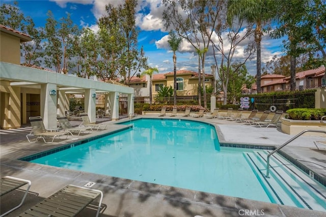 community pool with a residential view, a patio area, and fence