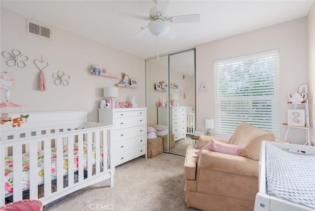 bedroom with a nursery area, a ceiling fan, a closet, carpet, and visible vents