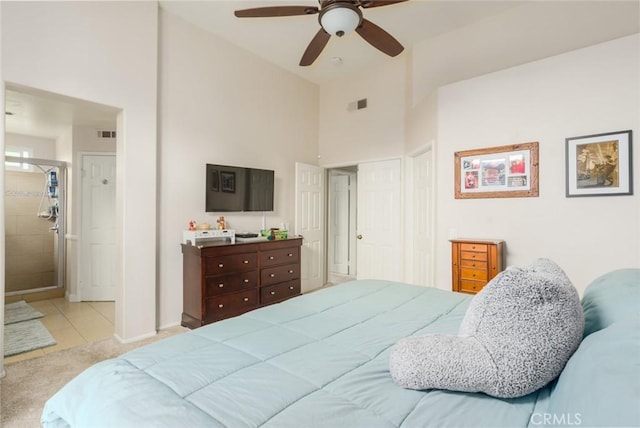 carpeted bedroom featuring tile patterned floors, ensuite bath, visible vents, and a high ceiling