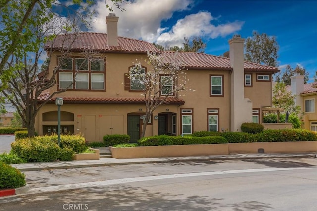 exterior space with a tiled roof, a chimney, and stucco siding