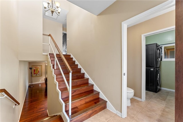stairs featuring baseboards, stacked washing maching and dryer, and an inviting chandelier