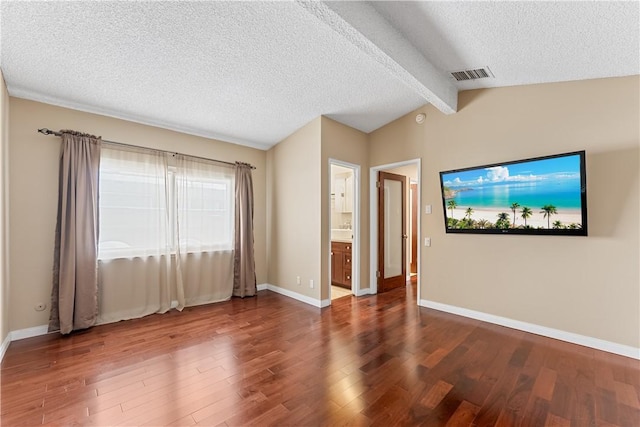unfurnished living room featuring a textured ceiling, visible vents, baseboards, wood finished floors, and vaulted ceiling with beams