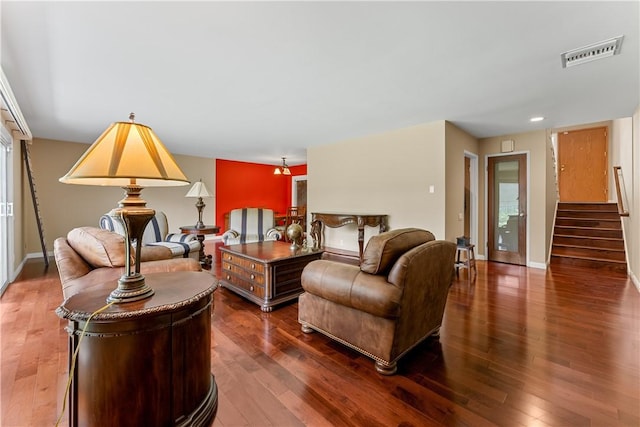 living room featuring stairs, visible vents, and wood finished floors