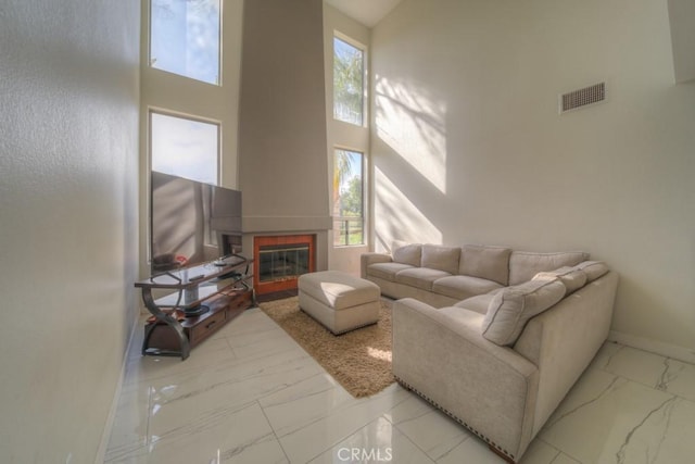 10917 Breezy Meadow Dr, Moreno Valley, CA 92557 - living room with a high ceiling, marble finish floor, visible vents, baseboards, and a glass covered fireplace