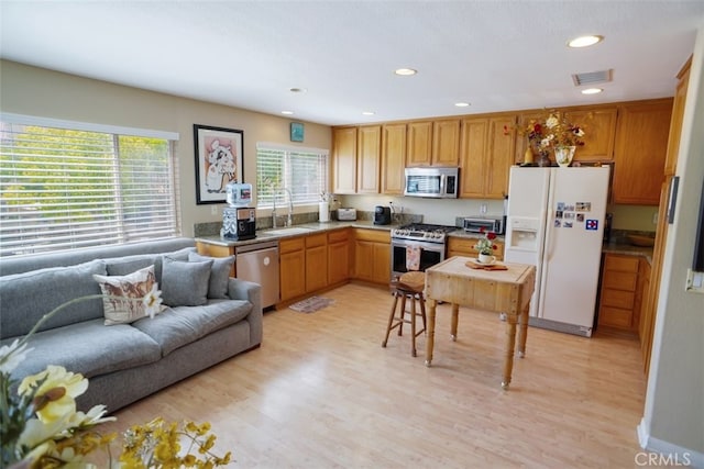 kitchen with recessed lighting, stainless steel appliances, a sink, light wood-type flooring, and open floor plan