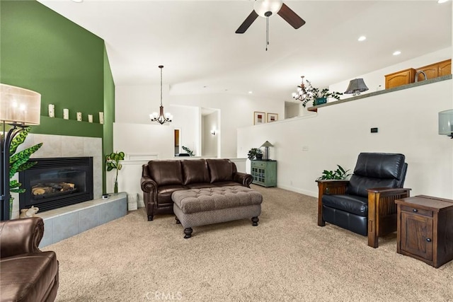living room featuring vaulted ceiling, a tiled fireplace, ceiling fan with notable chandelier, and light colored carpet
