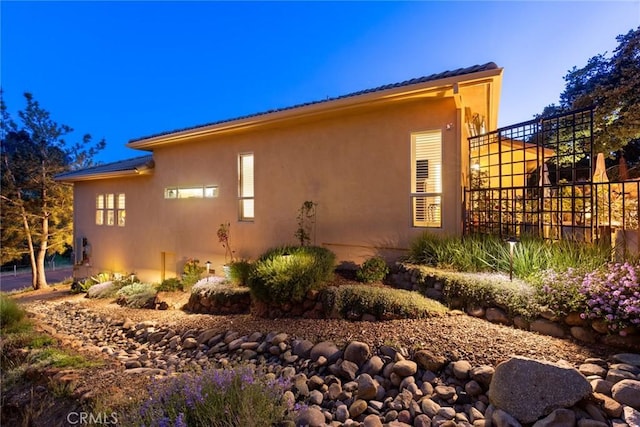view of side of property featuring fence and stucco siding