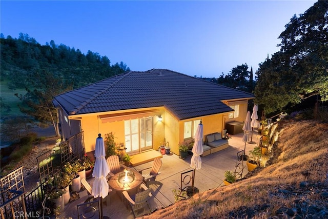 rear view of house featuring a tiled roof, a patio area, and stucco siding