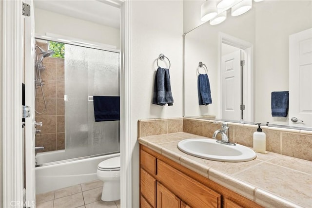 bathroom featuring toilet, tile patterned floors, bath / shower combo with glass door, and vanity