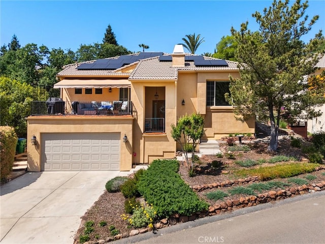 view of front facade with a tiled roof, solar panels, a balcony, concrete driveway, and stucco siding