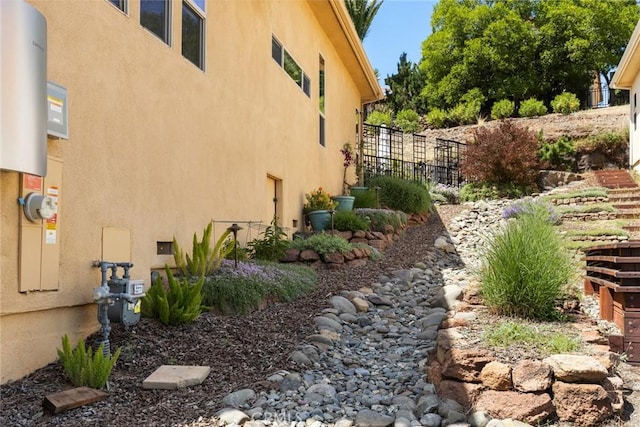 view of side of home featuring stucco siding and fence