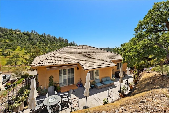rear view of house featuring fence, a patio, stucco siding, and a tile roof