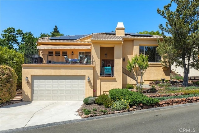 multi unit property with roof mounted solar panels, stucco siding, and a balcony