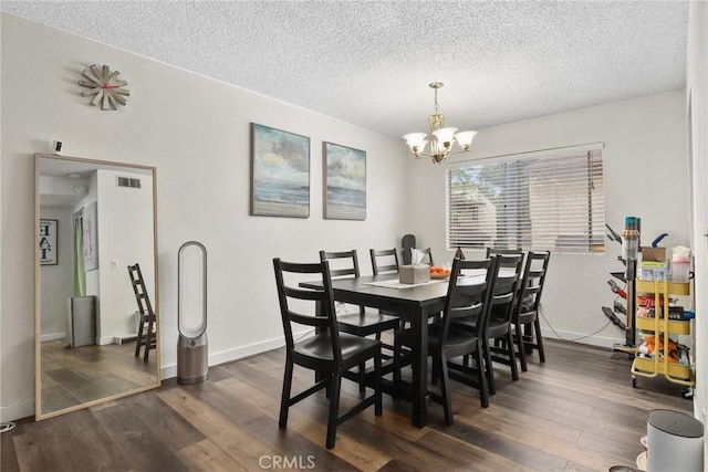 dining space featuring visible vents, a chandelier, a textured ceiling, and dark wood-style floors