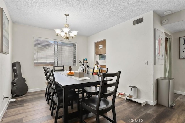 dining area with a textured ceiling, visible vents, a notable chandelier, and dark wood-style flooring