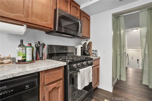 kitchen with brown cabinetry, baseboards, stainless steel appliances, and dark wood-type flooring