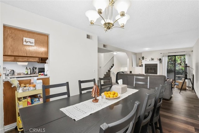 dining space with an inviting chandelier, stairway, dark wood-style flooring, a fireplace, and visible vents