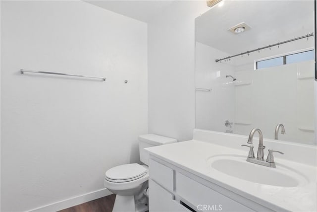 bathroom featuring toilet, vanity, wood finished floors, and baseboards