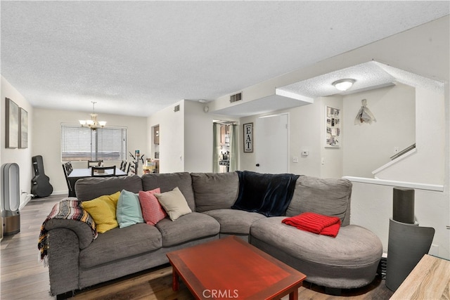 living area featuring a chandelier, visible vents, wood finished floors, and a textured ceiling