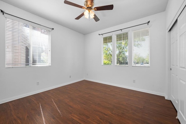unfurnished bedroom with a ceiling fan, baseboards, a closet, and dark wood-style flooring
