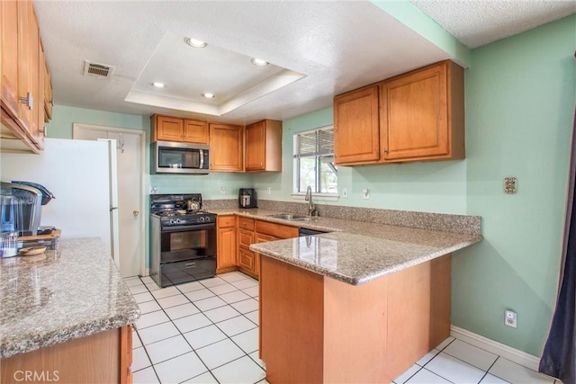 kitchen featuring visible vents, a peninsula, stainless steel microwave, a sink, and black range with gas cooktop