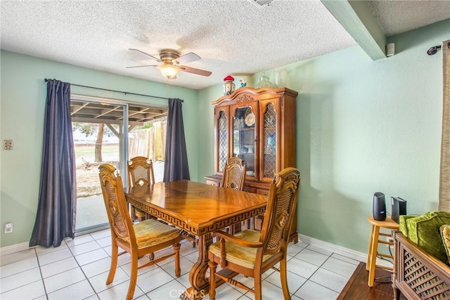 dining space with light tile patterned floors, baseboards, a ceiling fan, and a textured ceiling