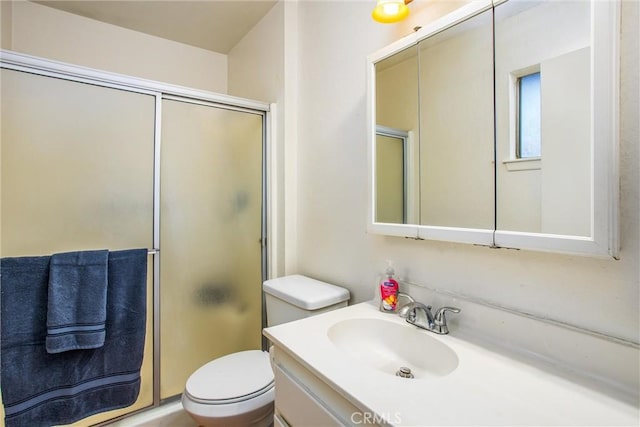 full bathroom featuring vanity, a shower with door, and toilet