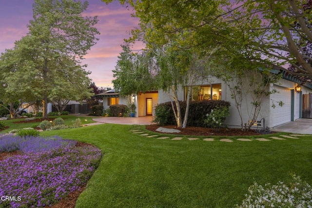 view of front facade featuring a front lawn, an attached garage, and stucco siding