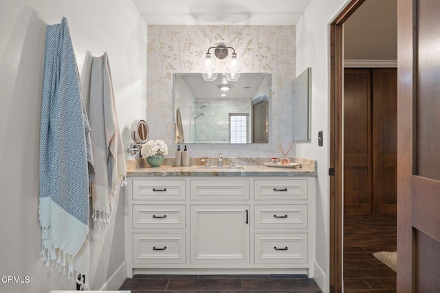 full bath featuring a shower, vanity, wood finish floors, and baseboards