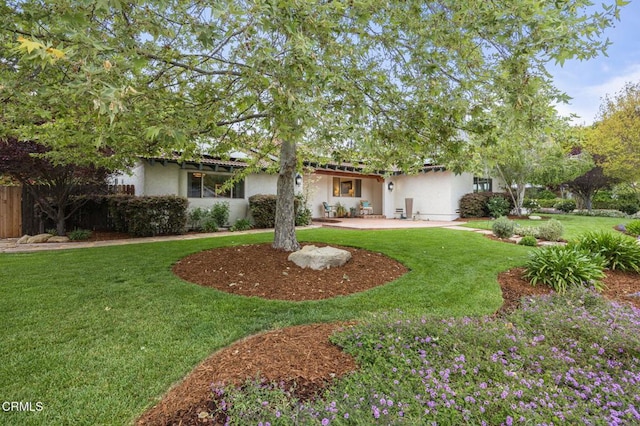 view of front facade featuring a front yard, stucco siding, and a patio area